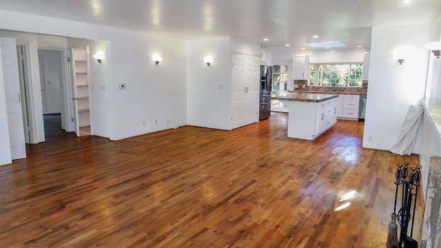 kitchen featuring a kitchen island, appliances with stainless steel finishes, dark wood finished floors, dark countertops, and white cabinets