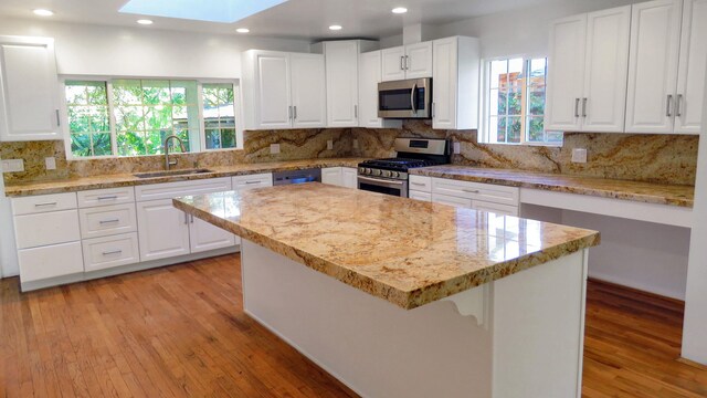 kitchen with a sink, stainless steel appliances, a skylight, and light wood-style floors