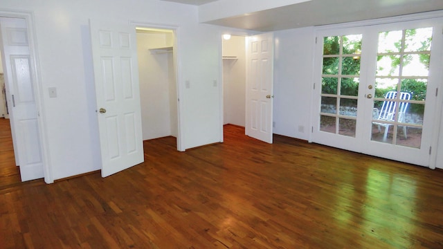 unfurnished bedroom featuring wood finished floors, french doors, and a walk in closet
