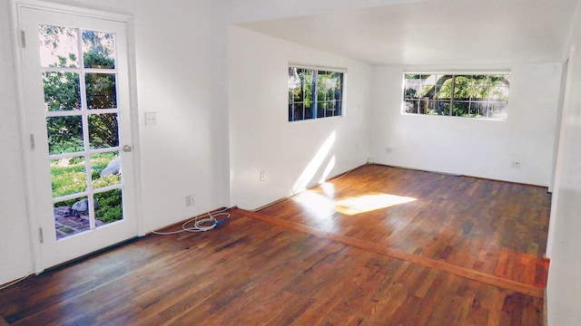 spare room with wood finished floors and vaulted ceiling