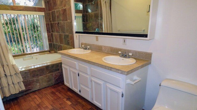 bathroom with double vanity, a bath, wood finished floors, and a sink