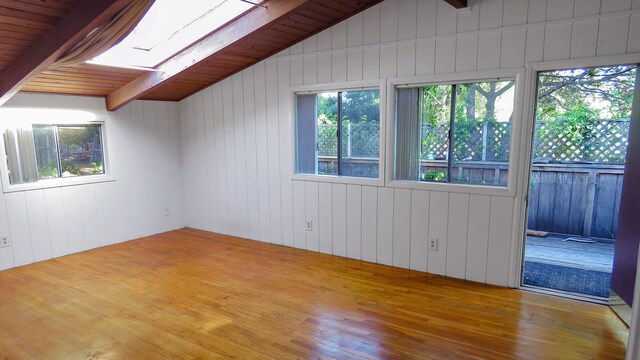 spare room with beamed ceiling, a skylight, wood ceiling, and hardwood / wood-style floors