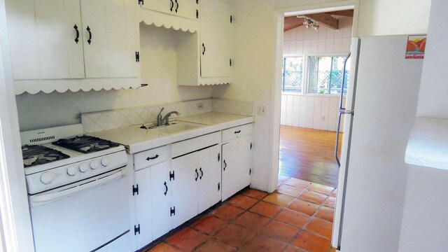 kitchen with light countertops, white cabinets, white appliances, tile patterned floors, and a sink
