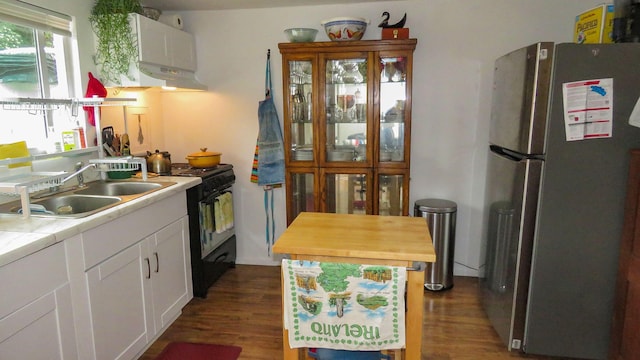 kitchen featuring white cabinets, gas stove, dark wood-type flooring, a sink, and freestanding refrigerator