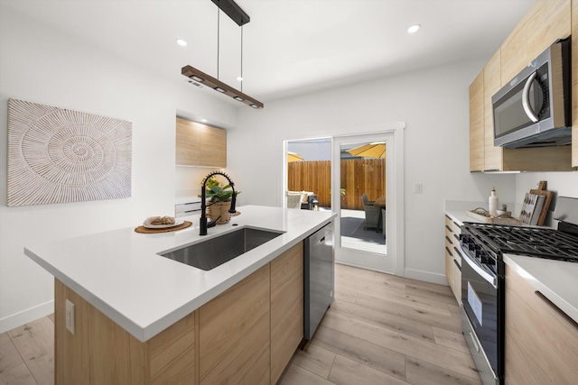 334 W Mission St, Santa Barbara, CA 93101 - kitchen featuring appliances with stainless steel finishes, a sink, modern cabinets, light brown cabinets, and light wood finished floors