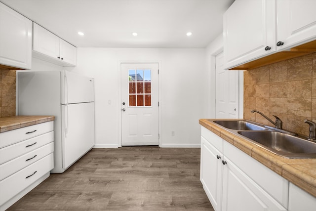 334 W Mission St, Santa Barbara, CA 93101 - kitchen with freestanding refrigerator, a sink, light wood-style flooring, decorative backsplash, and white cabinetry