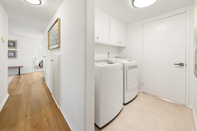 washroom featuring cabinet space, light wood-type flooring, and washing machine and clothes dryer