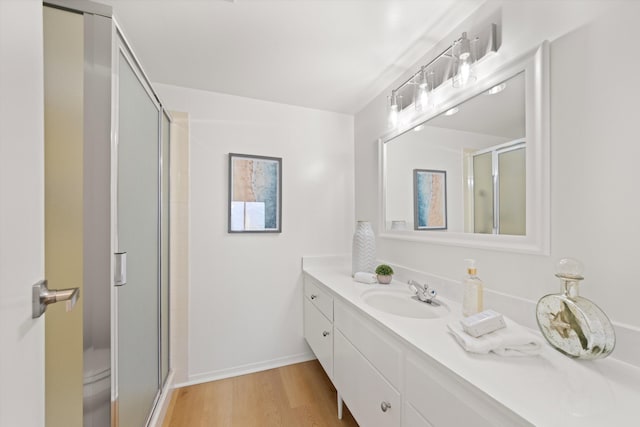 full bathroom with wood finished floors, toilet, vanity, baseboards, and a stall shower