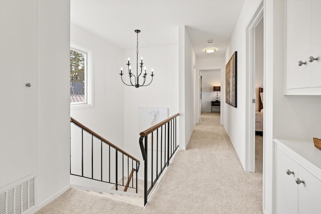 hall with an upstairs landing, light carpet, baseboards, a notable chandelier, and visible vents