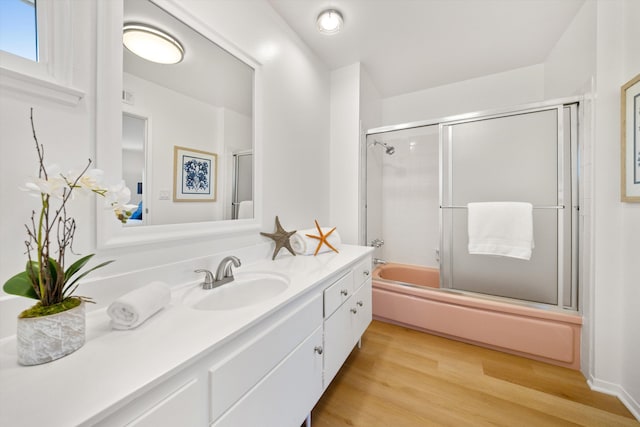 bathroom featuring visible vents, vanity, wood finished floors, and shower / bath combination with glass door