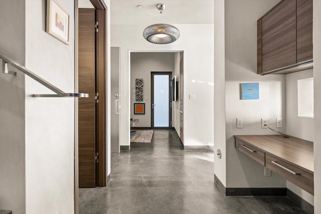 hall with concrete flooring and baseboards