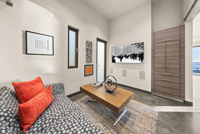 living area featuring concrete flooring and baseboards
