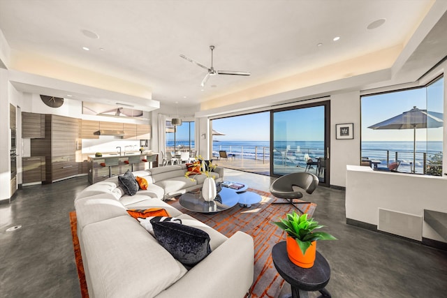 living room featuring a water view, ceiling fan, a wealth of natural light, and finished concrete floors