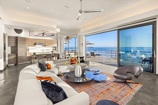 living area featuring a water view, a ceiling fan, recessed lighting, and concrete floors