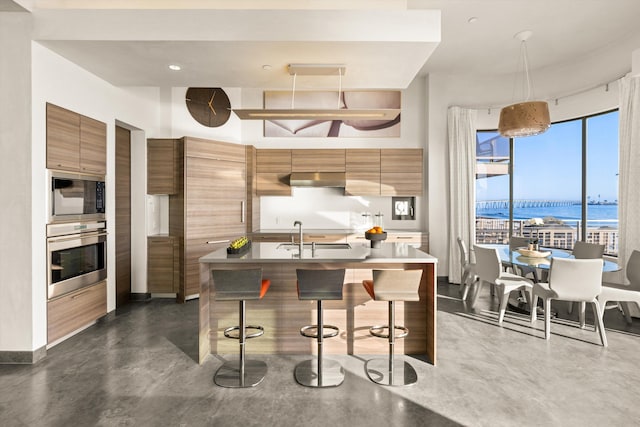 kitchen with black microwave, modern cabinets, stainless steel oven, and concrete floors