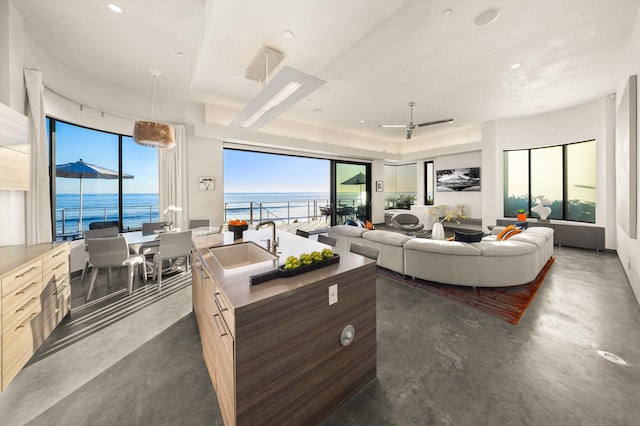 living area featuring concrete flooring, a tray ceiling, recessed lighting, and a water view