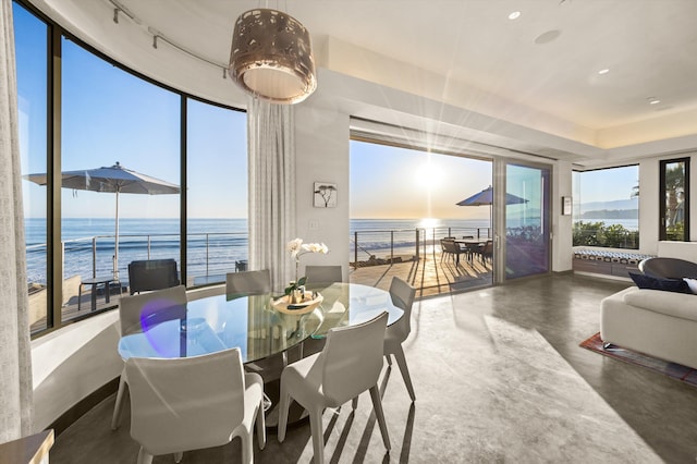 dining space with a water view, floor to ceiling windows, concrete floors, and recessed lighting