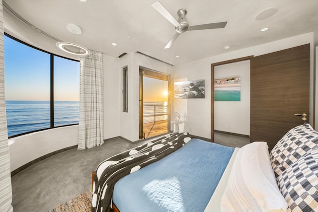 bedroom featuring finished concrete flooring, baseboards, ceiling fan, and a water view
