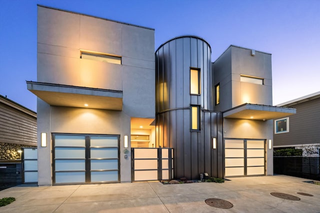 contemporary house with fence, an attached garage, board and batten siding, and concrete driveway