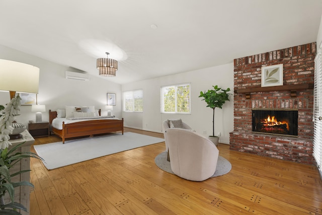 bedroom featuring a wall mounted air conditioner, a fireplace, and hardwood / wood-style flooring