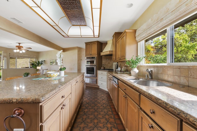kitchen with a kitchen island, a warming drawer, a sink, premium range hood, and backsplash