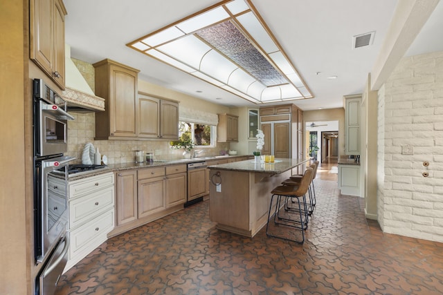 kitchen featuring a kitchen bar, stone counters, visible vents, a warming drawer, and a center island