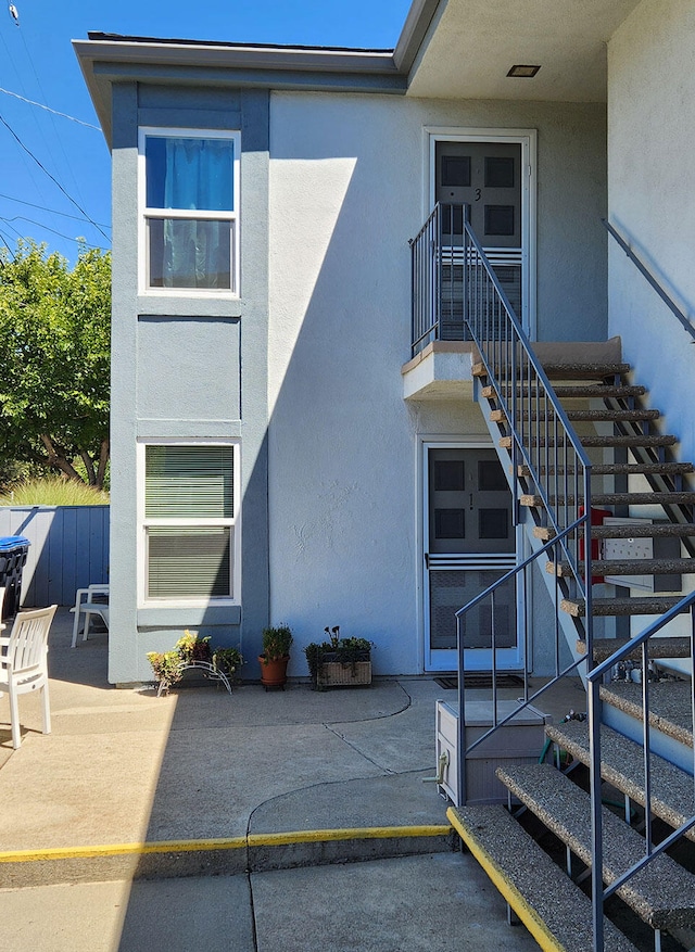 exterior space with a patio, stairway, stucco siding, and fence