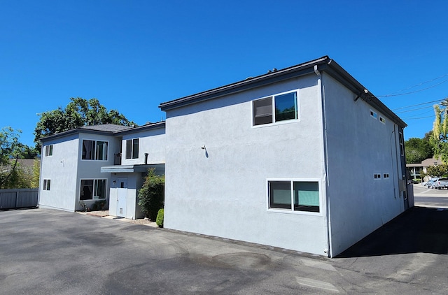 view of property exterior with stucco siding and fence