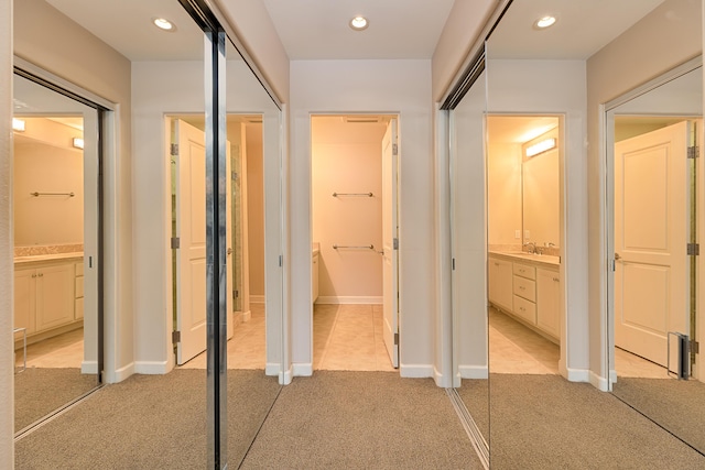 corridor with baseboards, recessed lighting, light carpet, and a sink