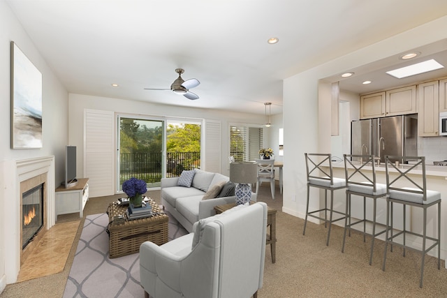 living area featuring recessed lighting, ceiling fan, a fireplace, and light colored carpet