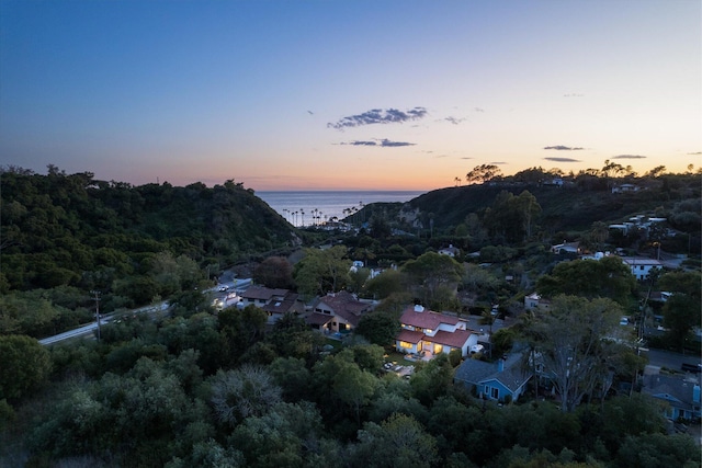 aerial view at dusk featuring a water view