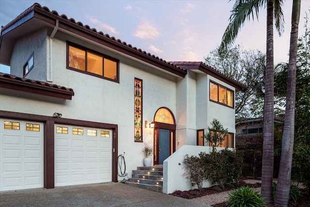 mediterranean / spanish home with a garage, stucco siding, concrete driveway, and a tile roof