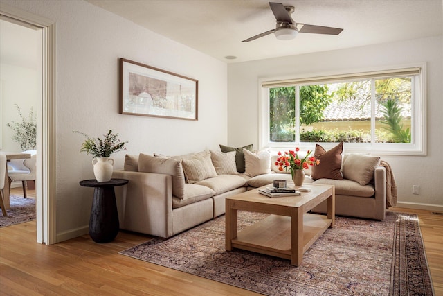 living area featuring wood finished floors, ceiling fan, and baseboards
