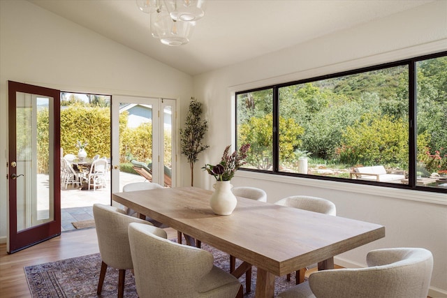 dining room featuring light wood-type flooring, a chandelier, and vaulted ceiling