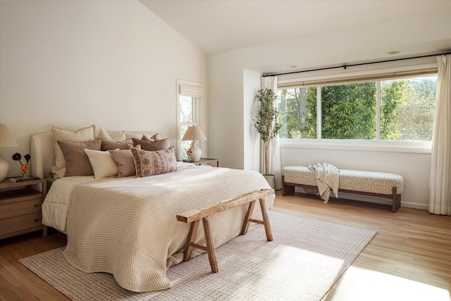 bedroom featuring baseboards, light wood-style floors, and lofted ceiling
