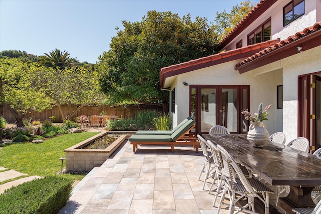 view of patio with outdoor dining space, french doors, and fence