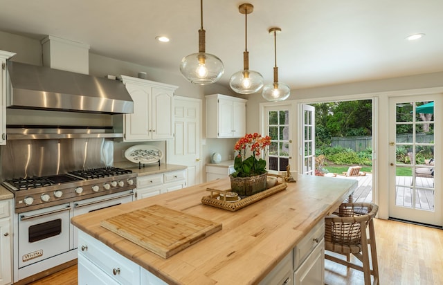 935 Arcady Rd, Santa Barbara, CA 93108 - kitchen with white cabinets, wall chimney range hood, wooden counters, double oven range, and pendant lighting