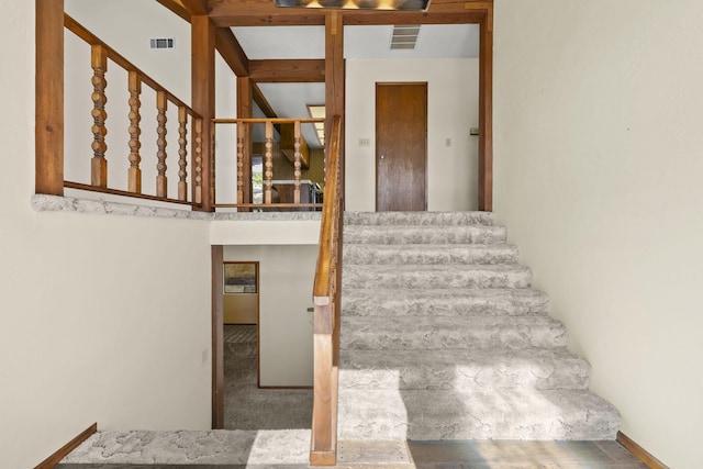 staircase featuring visible vents, beam ceiling, and carpet