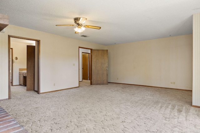 unfurnished bedroom with baseboards, wallpapered walls, a textured ceiling, carpet floors, and visible vents