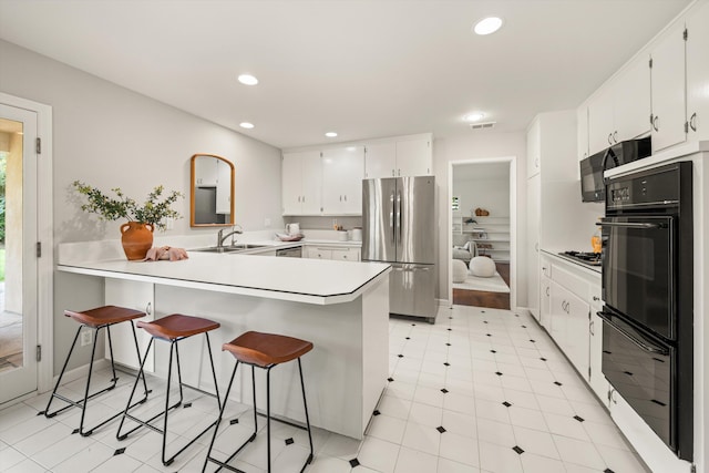 kitchen featuring black appliances, recessed lighting, a sink, and a peninsula