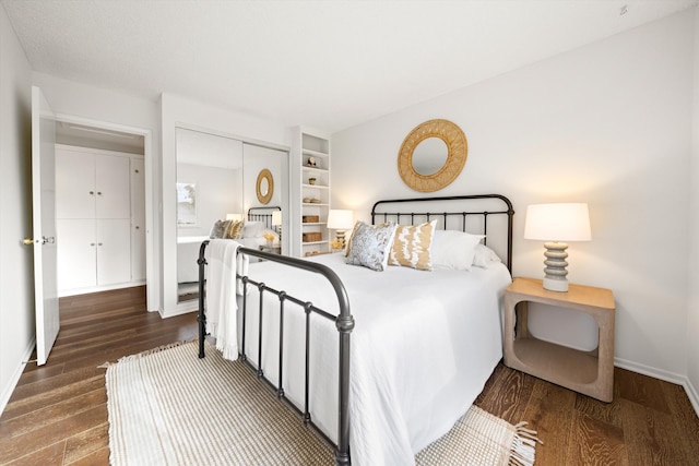 bedroom featuring wood finished floors, baseboards, and a closet
