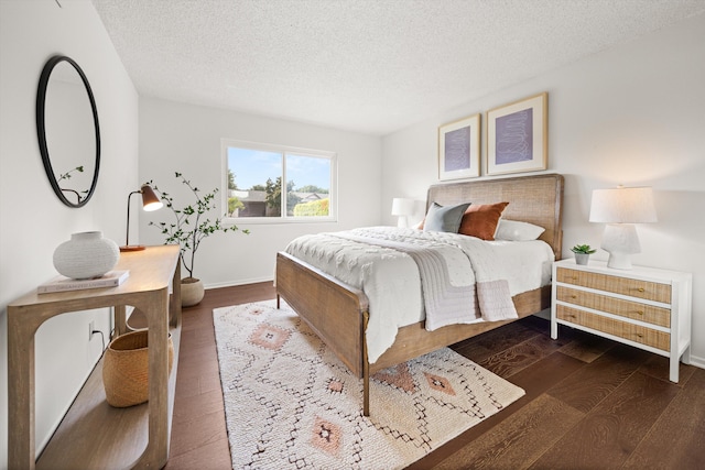bedroom with hardwood / wood-style floors, baseboards, and a textured ceiling