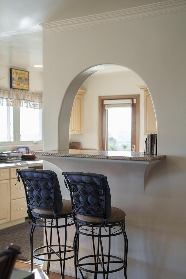 kitchen featuring light countertops, arched walkways, crown molding, and light brown cabinetry