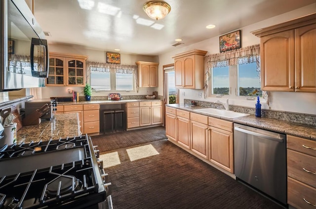 kitchen with glass insert cabinets, a sink, light brown cabinetry, recessed lighting, and stainless steel appliances