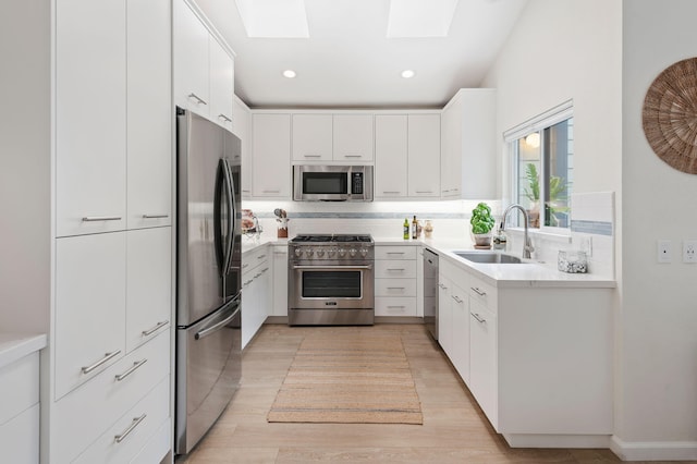 kitchen featuring a sink, stainless steel appliances, decorative backsplash, light wood-style flooring, and a skylight