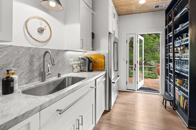 1435 Sycamore Canyon Rd, Santa Barbara, CA 93108 - kitchen featuring a sink, light stone counters, decorative backsplash, white cabinetry, and light wood finished floors