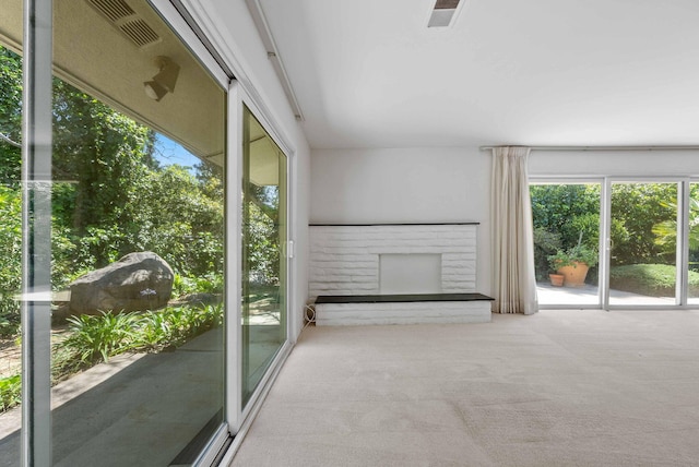 unfurnished living room featuring visible vents, carpet, a brick fireplace, and a healthy amount of sunlight