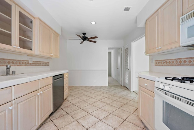 kitchen with tasteful backsplash, white appliances, light brown cabinets, and a sink