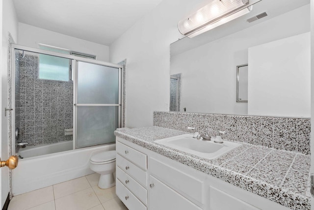bathroom featuring vanity, visible vents, toilet, combined bath / shower with glass door, and tile patterned floors