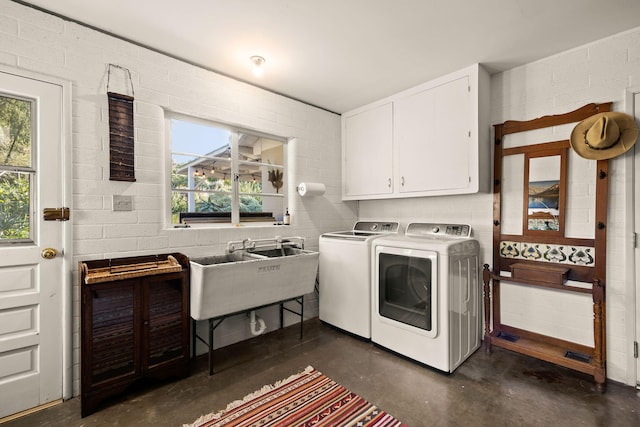 laundry room featuring washing machine and dryer, a sink, and cabinet space